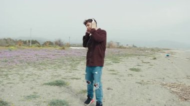 Müzik, sahilde kulaklıkla dans eden bir adama ritim veriyor. . 