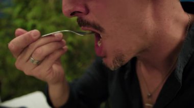 Yemek sırasında çatallı pizzadan Mozzarella yiyen adam. . 