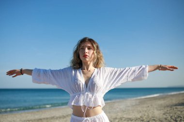 Kısa saçlı kız yazın okyanus kıyısındaki sahilde egzersiz yapıyor. .