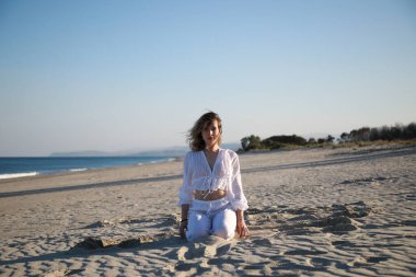 Yazın okyanusun kenarında Akdeniz kumu üzerinde beyaz giyinmiş bir kız. .