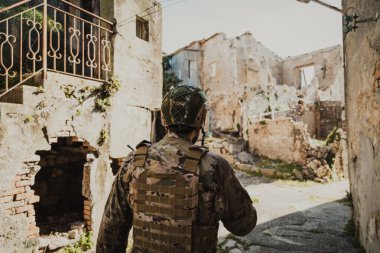 Üniformalı asker yıkılmış evlerin duvarlarını kontrol ediyor.. 