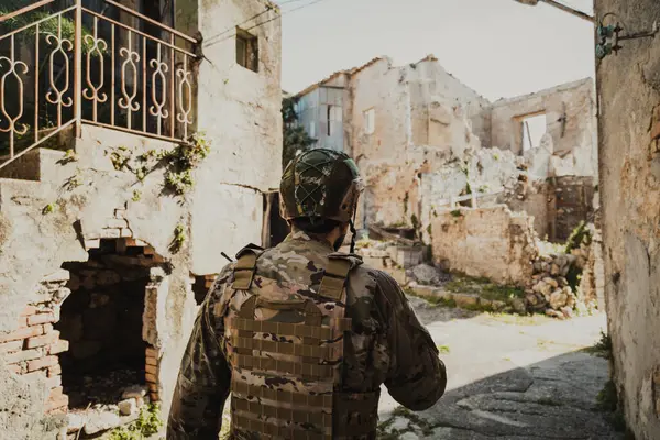 Üniformalı asker yıkılmış evlerin duvarlarını kontrol ediyor.. 