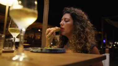 Plaj otelinde bir aperatifle yemeğe başlayan bir kadın. . 