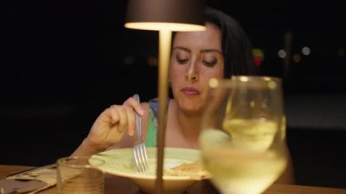 Lokantada dışarıda yemek yiyen bir kadının üzerine lamba ışığı. . 