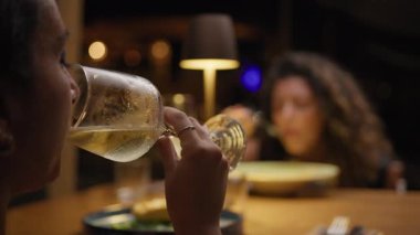 Bir arkadaşla yemek yerken kadehte şarap içen bir kadın. . 