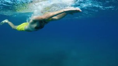 Yüzücü yarışa hazırlanmak için okyanus suyunda ısınıyor. .