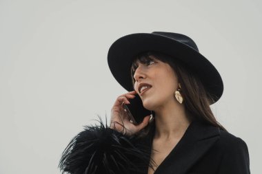 Kasaba parkında telefonla yürüyen siyahlı zarif bir kadın. . 