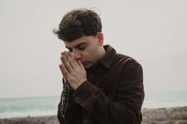 Adam kışın kıyıda tespih ve gözleriyle dua ediyor. . 