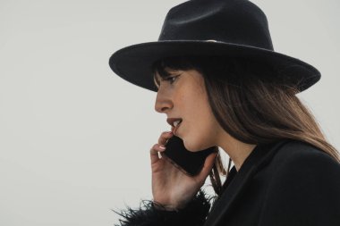 Kasaba parkında telefonla yürüyen siyahlı zarif bir kadın. . 