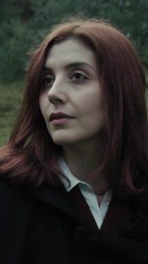 Bulutlu bir günde kırsalda pelerinli genç bir kadın..