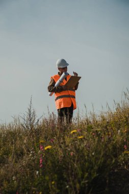 Mimar dışarıdaki büyük proje haritasına bakıyor. . 
