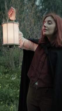 Bulutlu bir günde kırsalda pelerinli genç bir kadın..