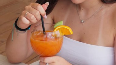 Kokteyli kamışla karıştıran kadın. 