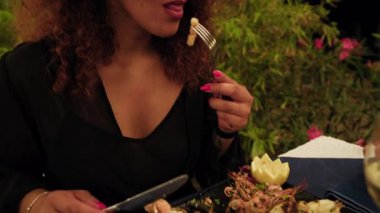 Sahildeki tatil yemeğinin başında ızgara aperatifin tadını çıkaran bir kadın. .