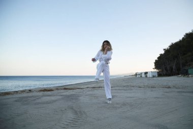 Yazın gün batımında sahilin kenarında beyaz giysili hip hop dansçısı kız. .