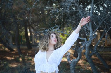 Genç Beyaz Giyinik Kadın Dağlardaki Çam Ormanı 'nın yakınında kollarını ısıtıyor .