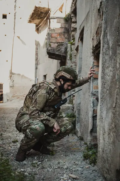 Asker, eski bir evin yıkılmış kapısından bakar.. 