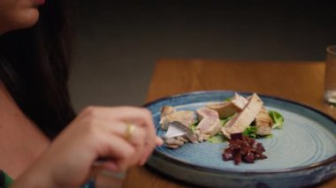 Bir kadın, ton balığının parçalarını kesmek için çatalı kullanıyor. .