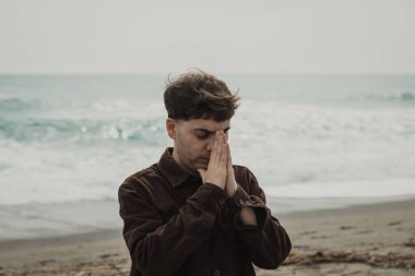 Adam kışın kıyıda tespih ve gözleriyle dua ediyor. . 