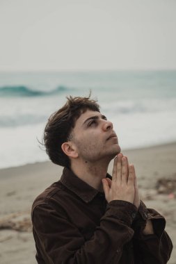 Adam kışın kıyıda tespih ve gözleriyle dua ediyor. . 