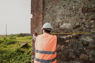 Dışarıdaki eski bina üzerinde Ölçüm Yapan İnşaatçı . 