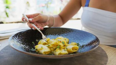 Kumsalda öğle yemeğinde makarna yiyen ve gülen bir kadın. .