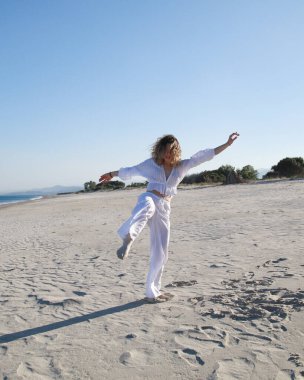 İtalyan Kız Beyaz Giysiler İçinde Okyanus 'un yanındaki yumuşak plajda Dans Ediyor .