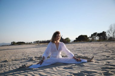 Yazın okyanusun kenarında Akdeniz kumu üzerinde beyaz giyinmiş bir kız. .