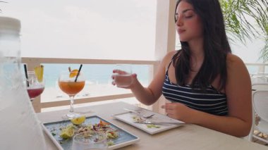 Deniz, kadının etrafını sarıp otelde öğle yemeği yiyor. . 