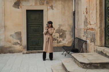 Ortaçağ şehir meydanında eski bir kamerayla çekim yapan bir kadın. .