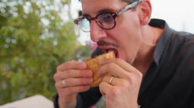 Sahilde sipariş edilen hamburgerin yarısını yiyen adam. .