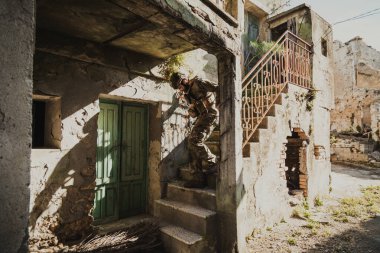 Genç asker dikkatle yıkılmış bir evin merdivenlerinden aşağı iniyor.. 