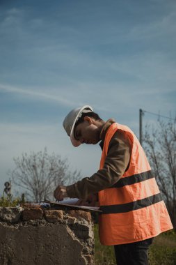 İnşaat alanına bakan ve not alan bir mühendis. . 