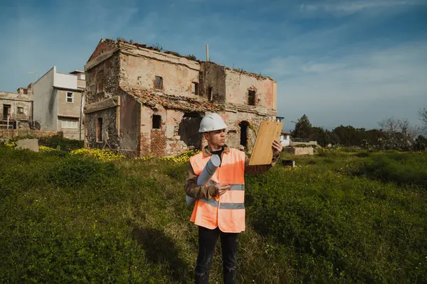 İnşaat alanındaki mühendis eski binaya bakıyor ve notlar alıyor.. 