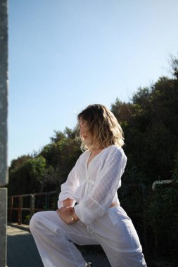 Beyazlar içindeki kız korkuluklara tutunarak dans ediyor. .