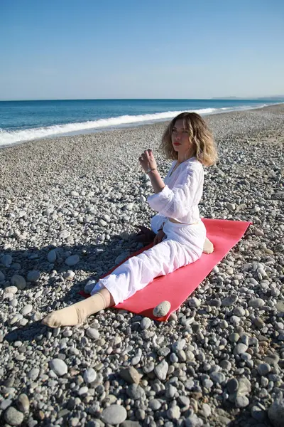 Sarı Saçlı Kız Okyanusun kenarındaki kumsalda Bacağını Gerer .