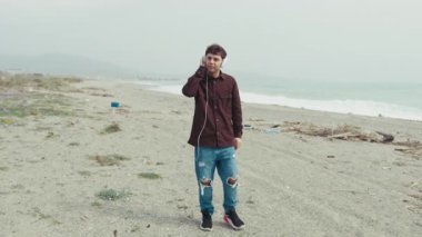 Genç adam sahilde bir kış günü müzik dinliyor. . 