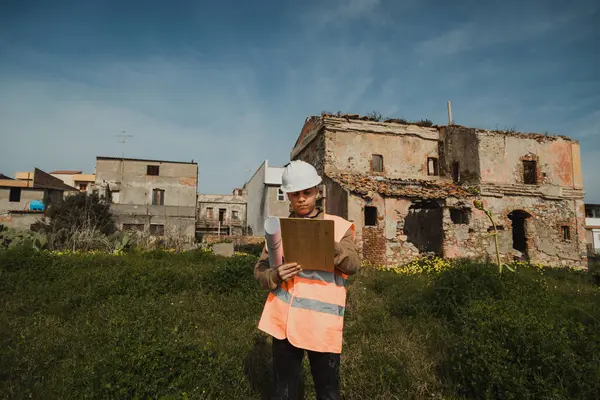 İnşaat alanındaki mühendis eski binaya bakıyor ve notlar alıyor.. 