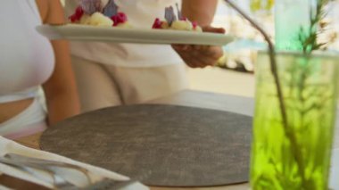 Garson, plajdaki restoranda morina balığı tabağı teslim ediyor..