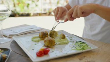 Adam oteldeki gurme balığı Au Gratin Dish 'i kesmek için çatal ve bıçak kullanıyor. . 