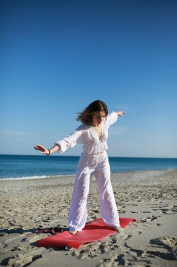 Kısa saçlı kız yazın okyanus kıyısındaki sahilde egzersiz yapıyor. .