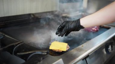 Şef ızgaranın üstüne çedar koyuyor. . 