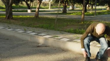 Adam bağcıklarını bağlamak için yol kenarında oturur..