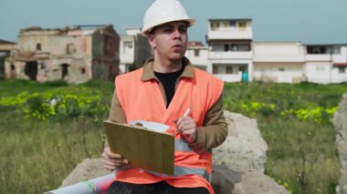 Bir kayanın üzerinde oturmuş not alan bir mühendis. . 