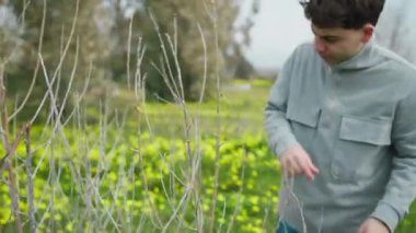 Dışarıdaki adam küçük çıplak ağaç dallarına bakıyor. . 