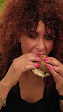 Dışarıdaki restoranda balıkla yapılan hamburgere ısırık veren bir kadın. . 