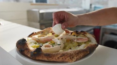 Şef Mozzarella 'yı Ahtapot Ahtapot PIzza' nın üstüne koyuyor.