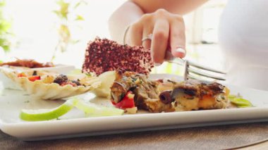 Bir restoranda yazın tabaktan balık aperatifi kesen bir kadın..