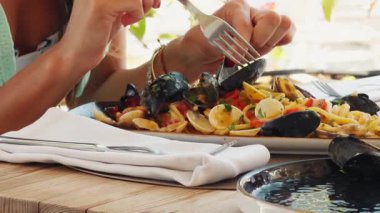 Gülümseyen kadın, sahil restoranında spagettiyle yemek yediği için mutlu. . 