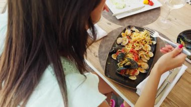 Gülümseyen kadın, sahil restoranında spagettiyle yemek yediği için mutlu. . 